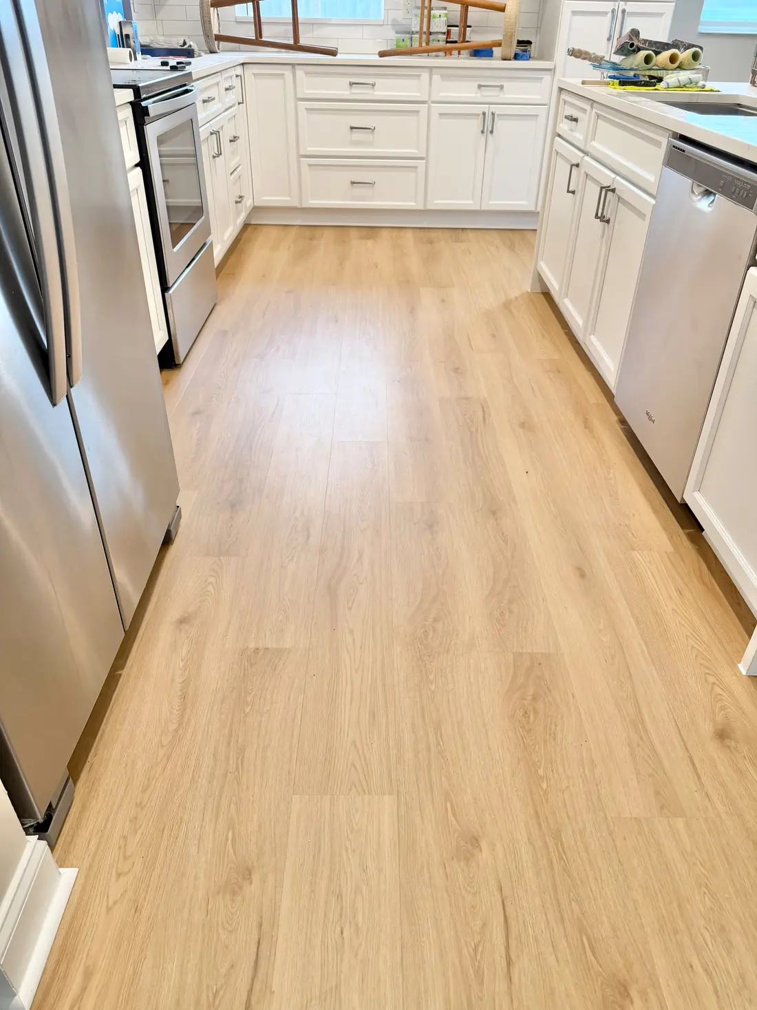 New light oak LVP flooring in a kitchen with white cabinets