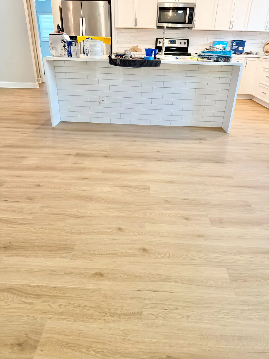 Light oak LVP flooring running from the kitchen island into the open living area